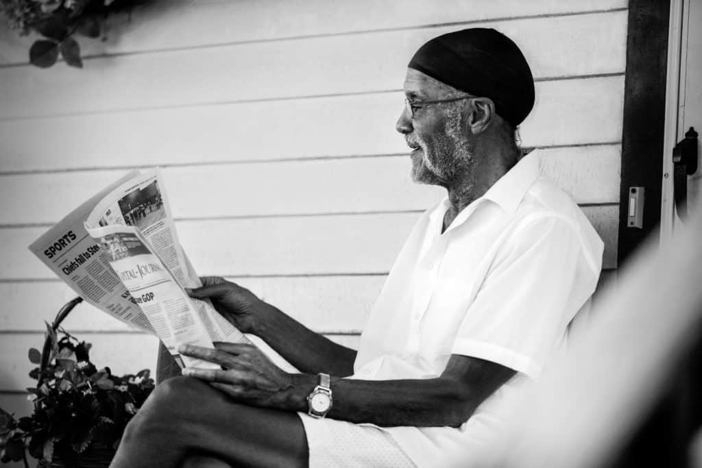 man reading a newspaper on front porch