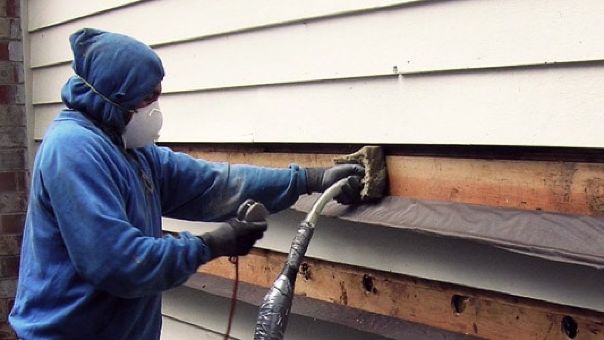 Weatherization professional adding insulation to home's exterior siding